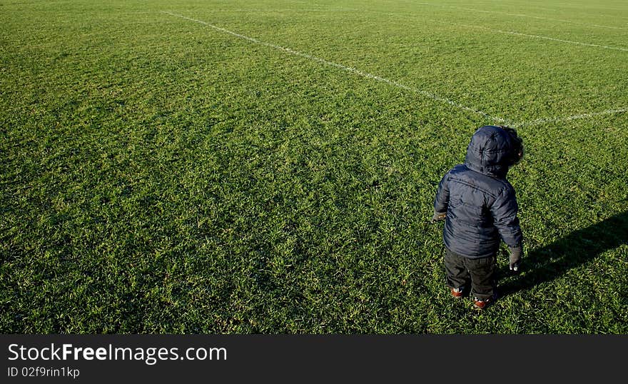 Little boy/toddler standing on football pitch at park. Little boy/toddler standing on football pitch at park