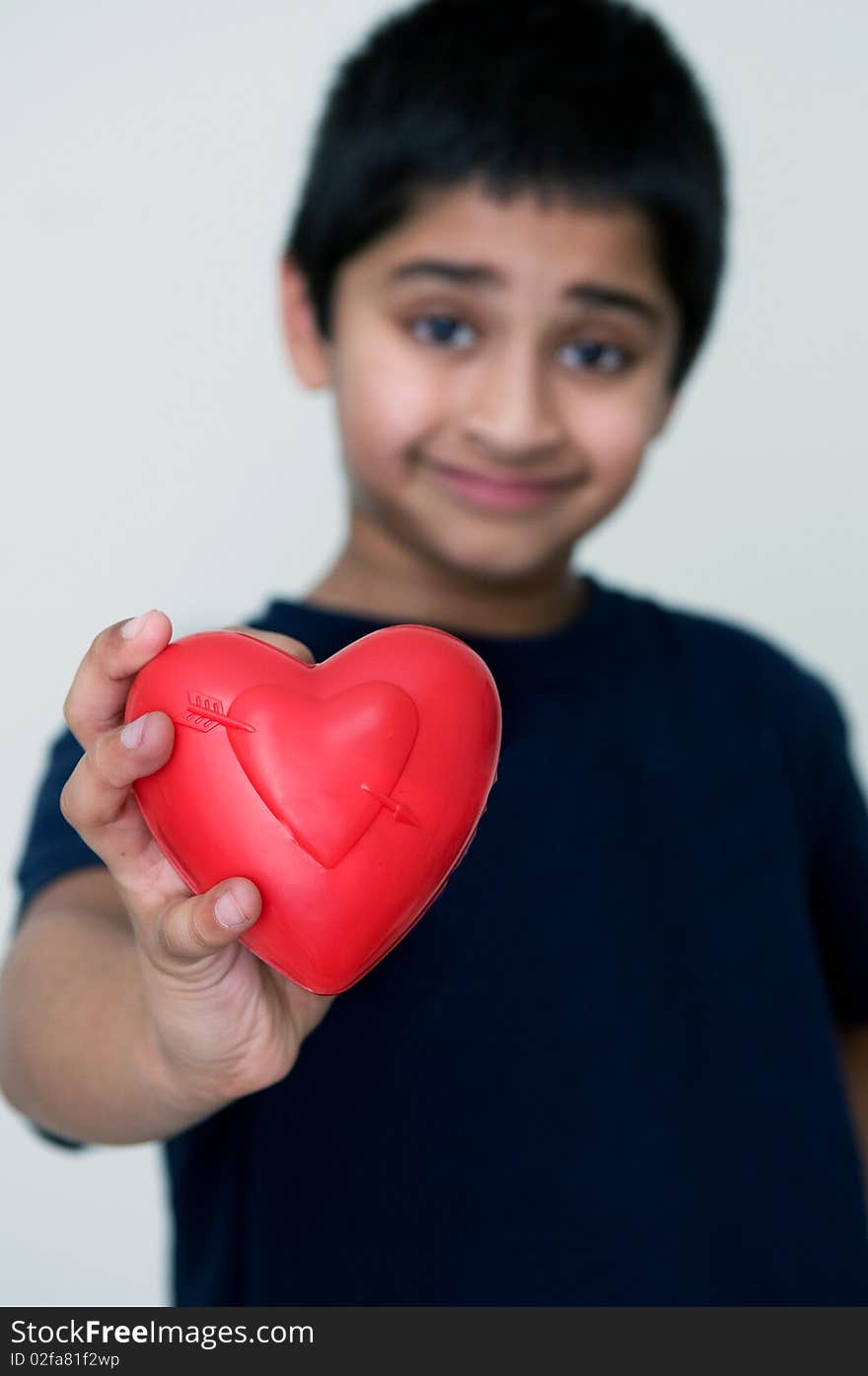 An handsome Indian kid holding out a red heart. An handsome Indian kid holding out a red heart