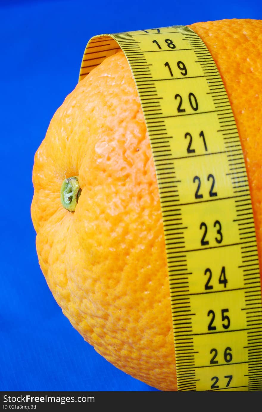 An orange and a measuring tape isolated on blue concepts of healthy diet