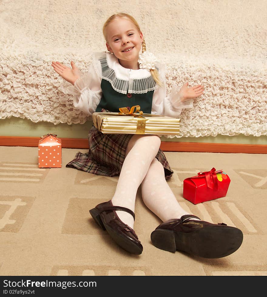 The girl sits on a floor with boxes of gifts. The girl sits on a floor with boxes of gifts