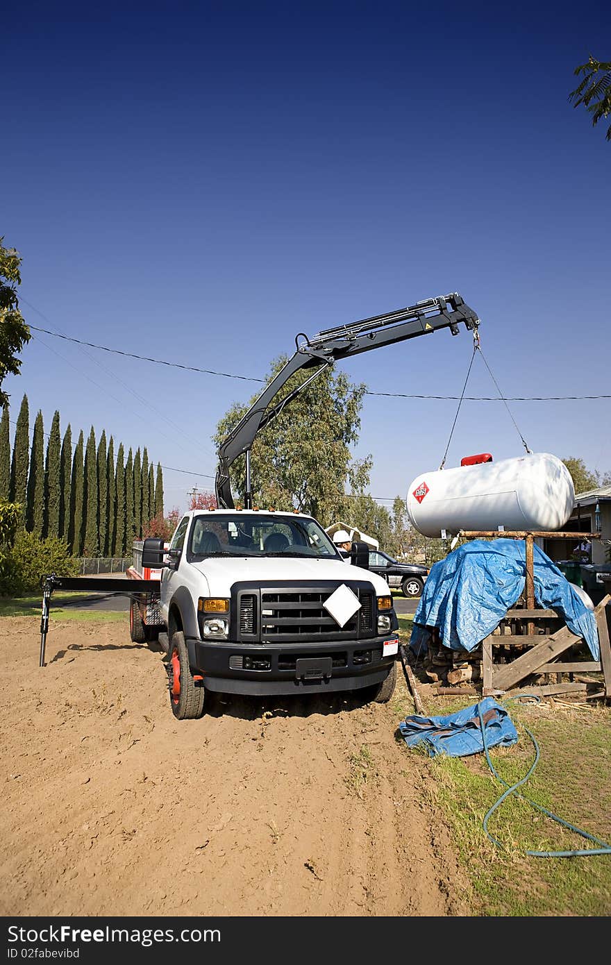 Crane in operation lifting a large gas tank