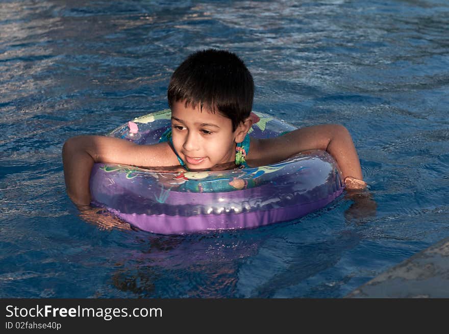 An handsome indian boy swimming happily in the pool