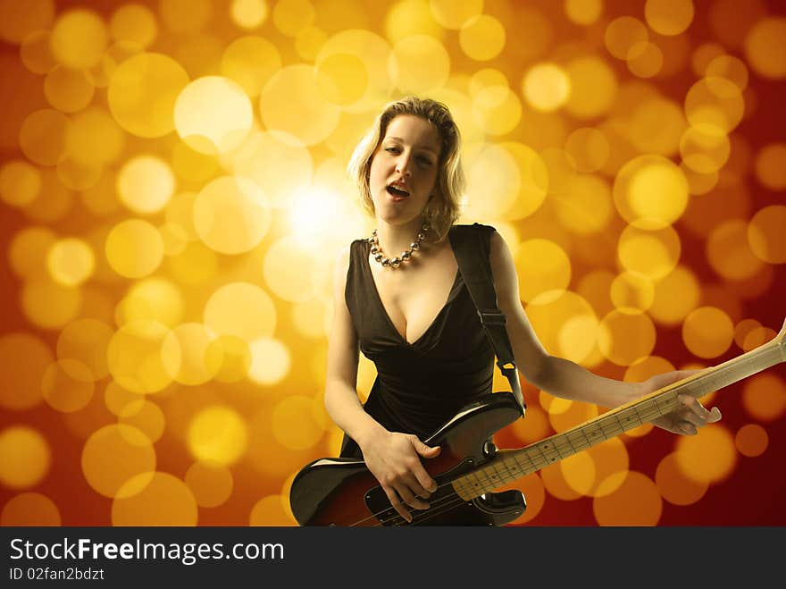 Portrait of a young woman singing and playing the bass guitar with glitters on the background. Portrait of a young woman singing and playing the bass guitar with glitters on the background