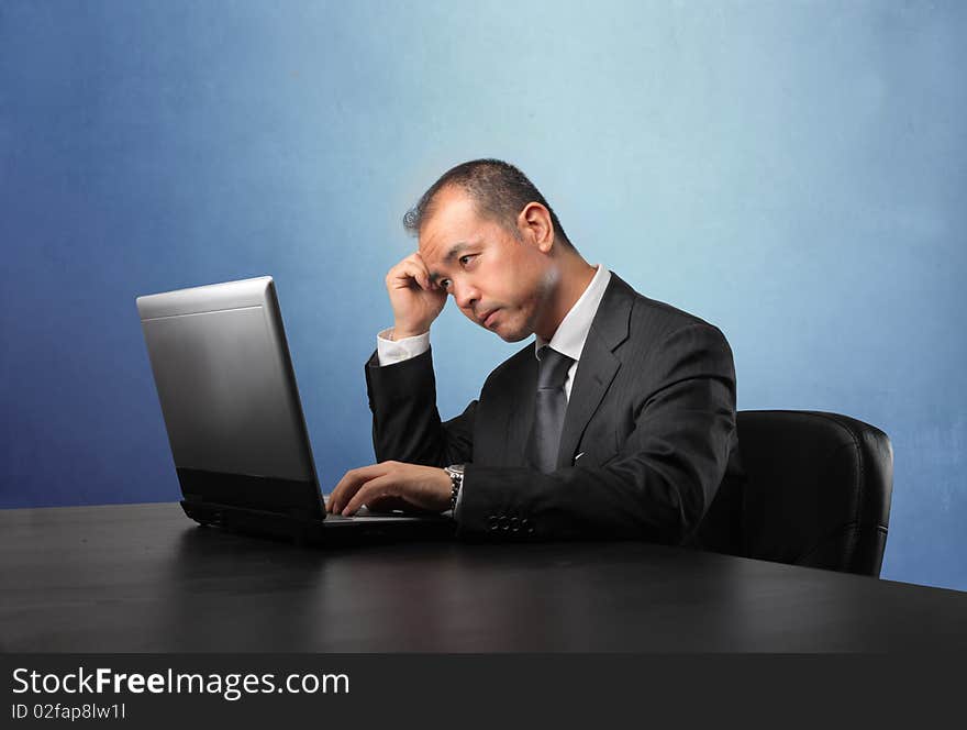 Japanese businessman sitting in front of a laptop and thinking