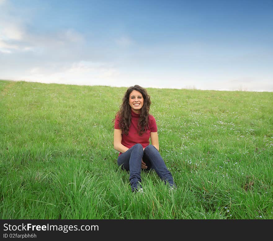 Smiling young woman sitting on a green meadow. Smiling young woman sitting on a green meadow