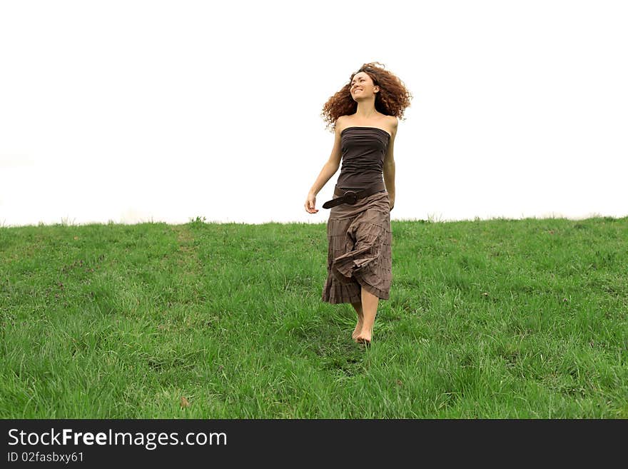 Smiling red haired woman walking on a green meadow. Smiling red haired woman walking on a green meadow