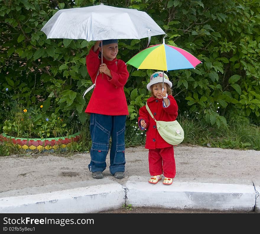 The boy and the girl stand with umbrellas. The boy and the girl stand with umbrellas