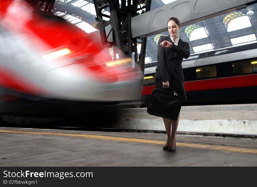 Businesswoman standing on the platform of a train station and looking at her watch. Businesswoman standing on the platform of a train station and looking at her watch