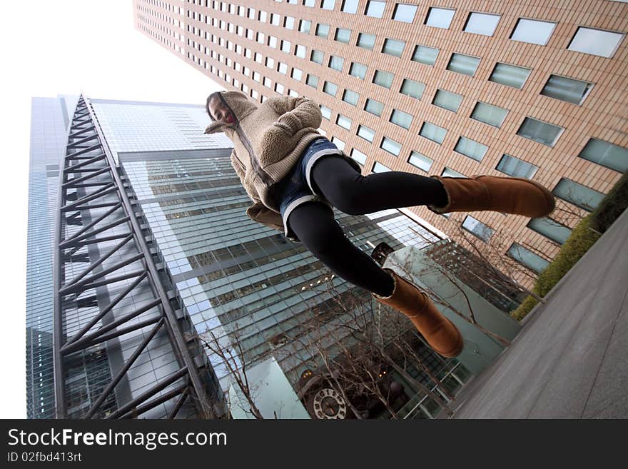 Young Japanese girl jumping in front of buildings