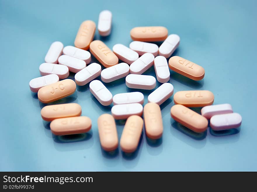 White Capsules and yellow pills on a blue background. White Capsules and yellow pills on a blue background