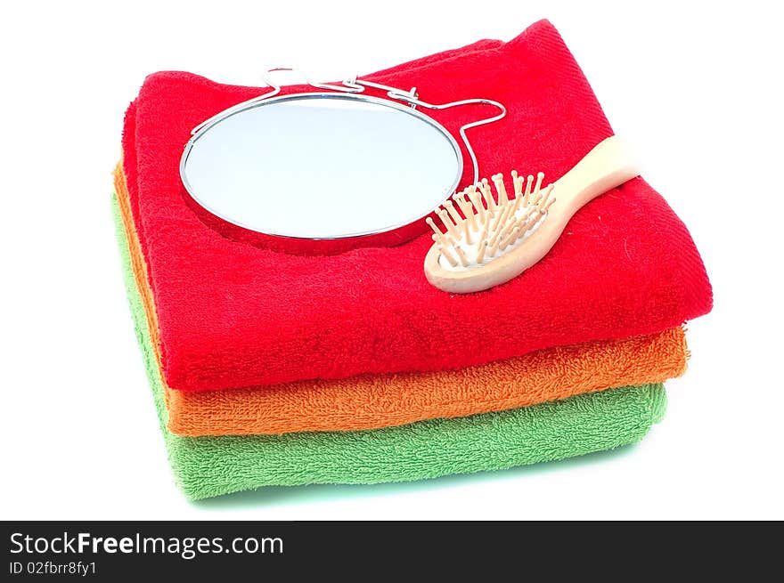 Bright fluffy towels a hairbrush and a mirror on a white background. Bright fluffy towels a hairbrush and a mirror on a white background