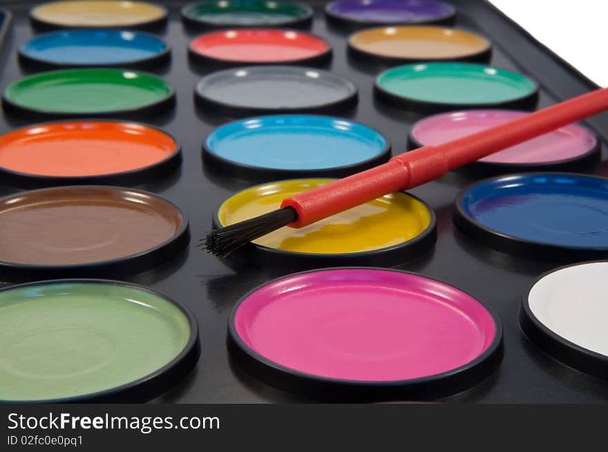 Close up of many dry, round, coloured watercolour paint tablets with paintbrush. Close up of many dry, round, coloured watercolour paint tablets with paintbrush.