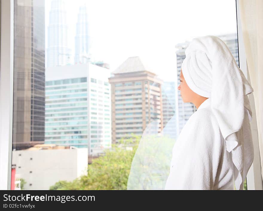 Pretty female standing by a window looking outside