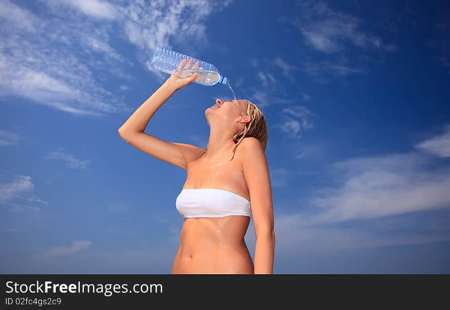 Hot woman spilling cold water. Blue sky on background.