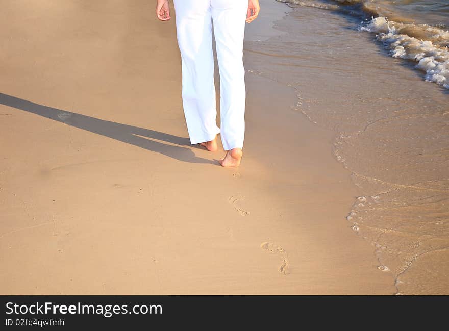 Girl waking on the beach leaving footprints on the sand. Girl waking on the beach leaving footprints on the sand