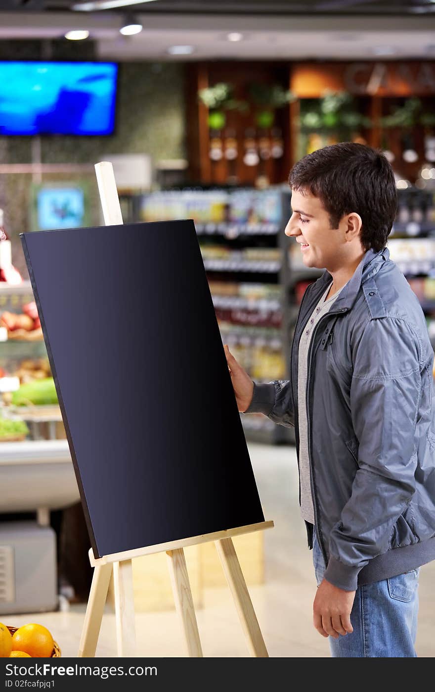 The young man faces to an empty board in shop. The young man faces to an empty board in shop