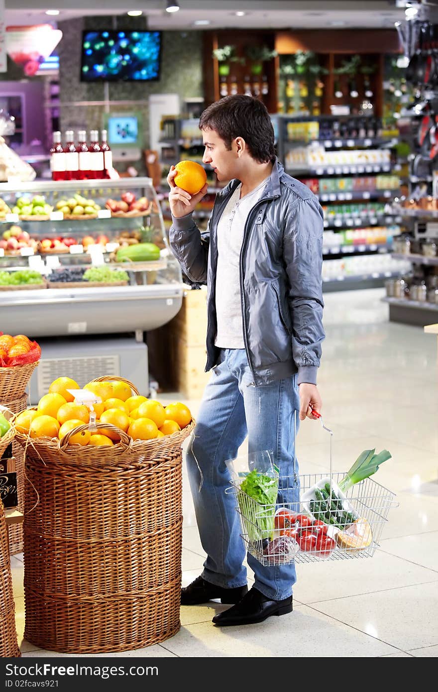 The man chooses a grapefruit in shop. The man chooses a grapefruit in shop