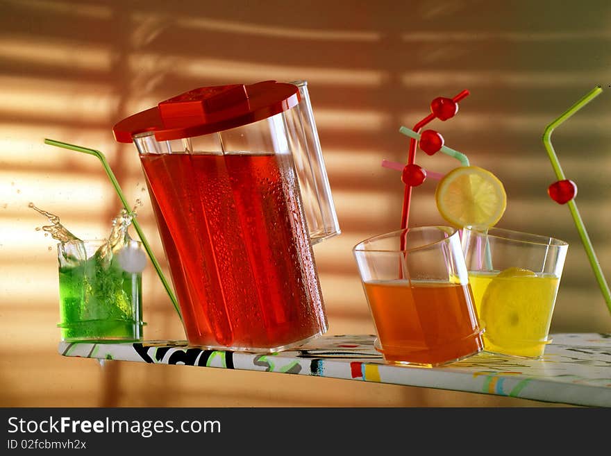 Jar and glasses with colourful drinks and funny straws