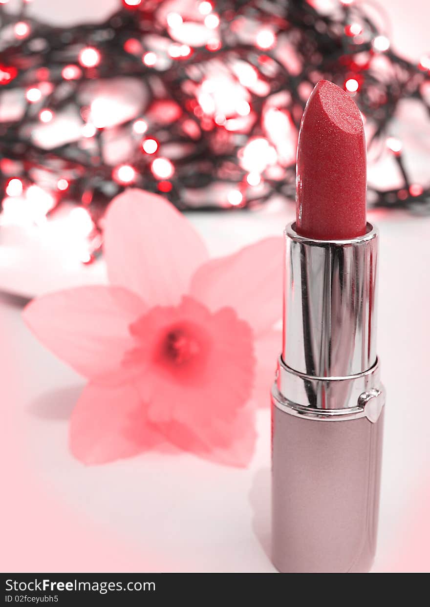 Red lipstick and pink flower on interesting background with lights