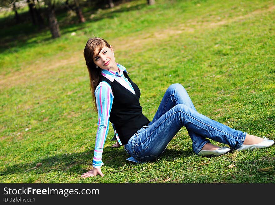 Teen girl relaxing in the park on the green grass