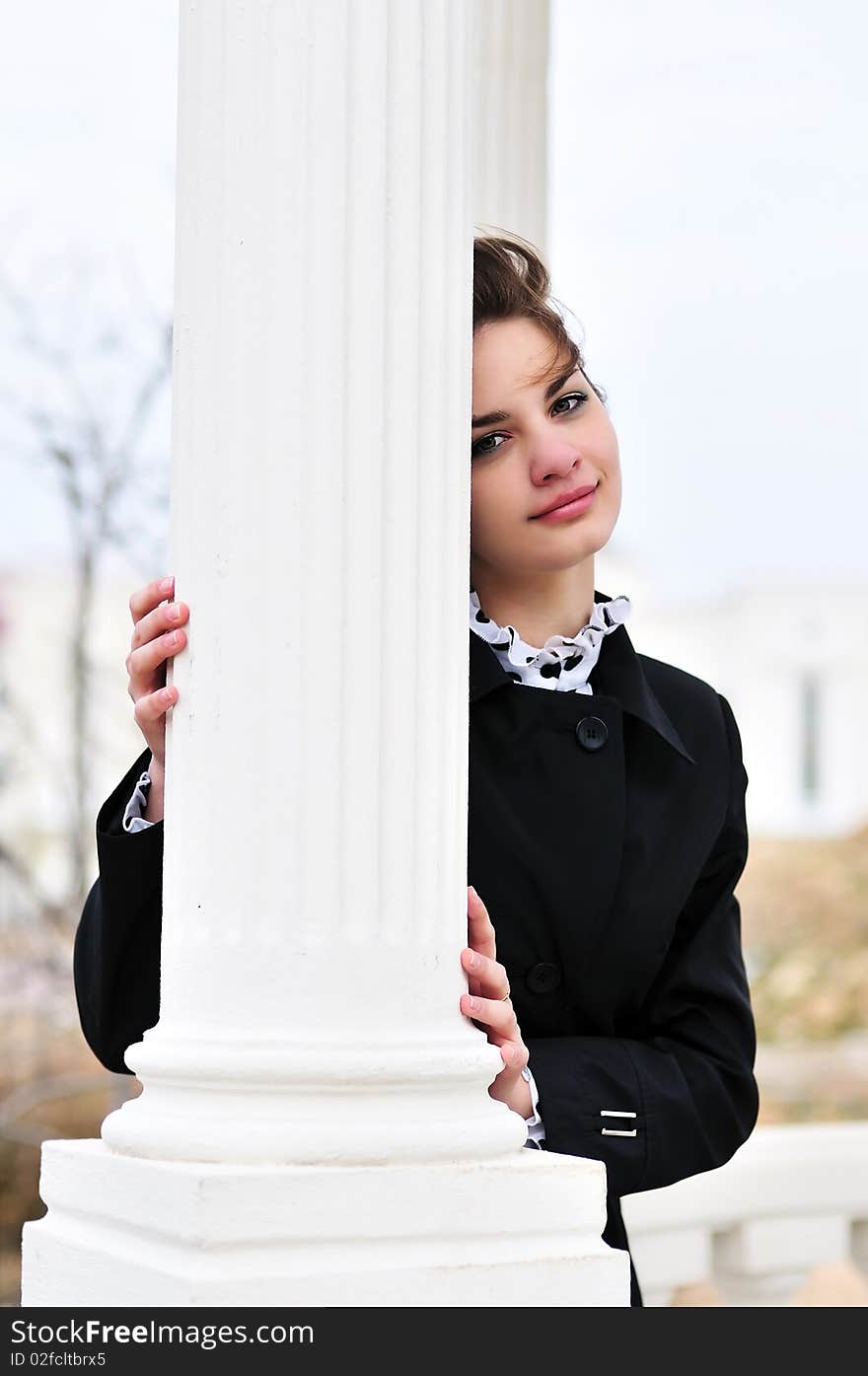 Teen beautiful girl standing behind white column. Teen beautiful girl standing behind white column