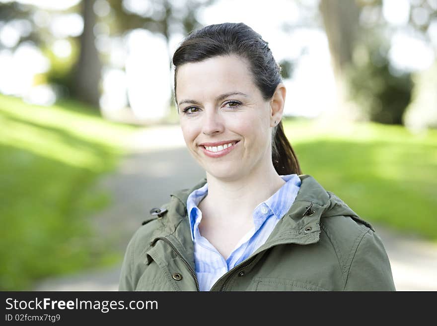 Portrait of a Pretty Young Woman Outdoors in a Park Smiling To Camera. Portrait of a Pretty Young Woman Outdoors in a Park Smiling To Camera