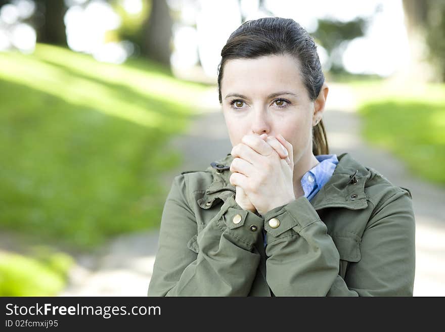 Pretty Young Woman in a Park Blowing on Her Hands. Pretty Young Woman in a Park Blowing on Her Hands