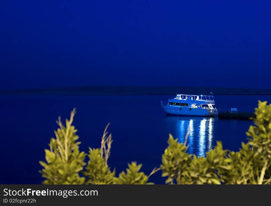 Motor yacht moored to jetty at night