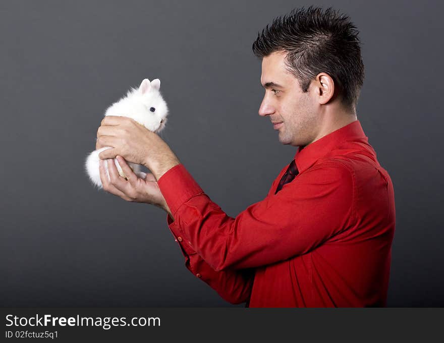 Handsome young man holding baby rabbit. Handsome young man holding baby rabbit