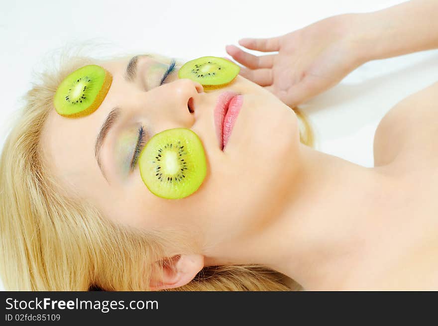 Beauty girl with kiwi on cheeks over white background. Beauty girl with kiwi on cheeks over white background