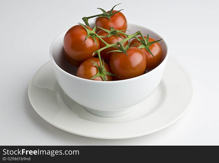 White bowl full of vine tomatoes. White bowl full of vine tomatoes