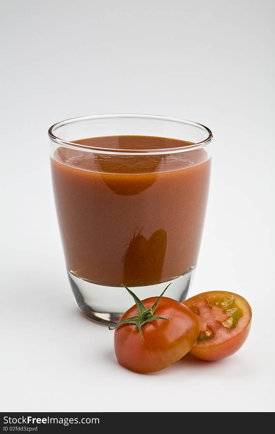 Glass of tomato juice on white with sliced tomato