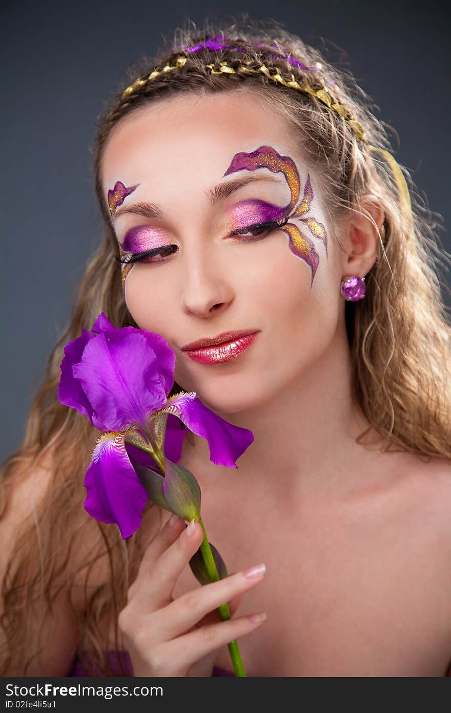 Beautiful girl with bright make-up holding purple iris. Beautiful girl with bright make-up holding purple iris