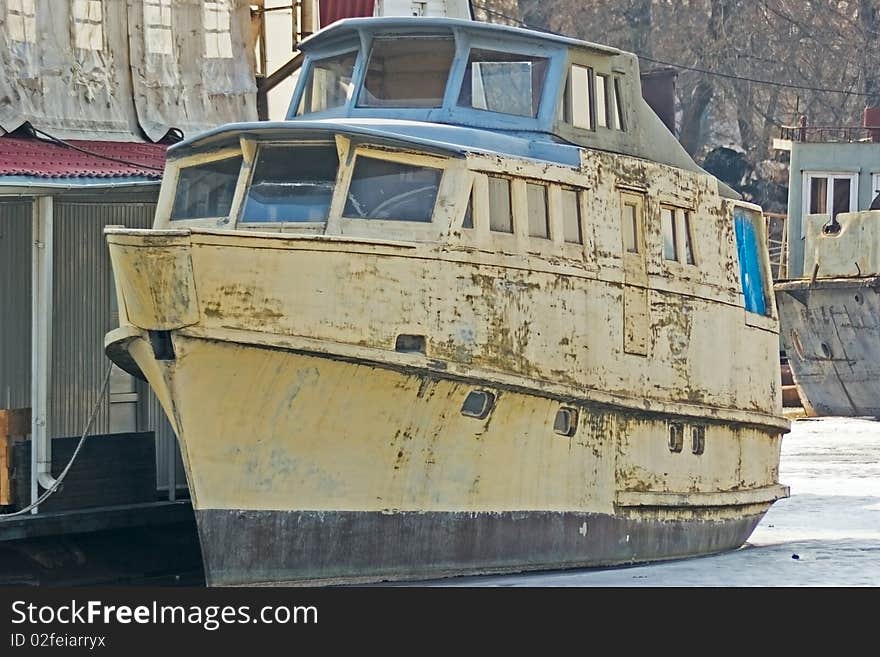 Old boat standing at the dock of the frozen bay