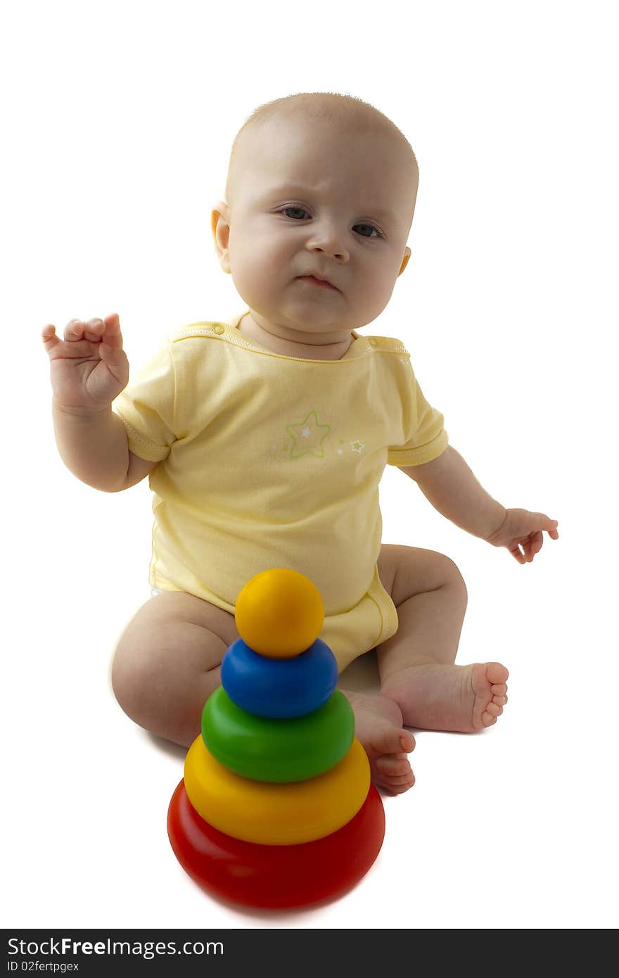 The baby of 6-7 months sits with a pyramid and is angry, hands in the parties