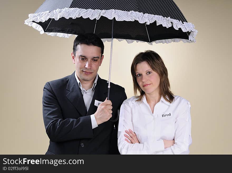 Fired man and woman showing identical situation and staying under the same umbrella