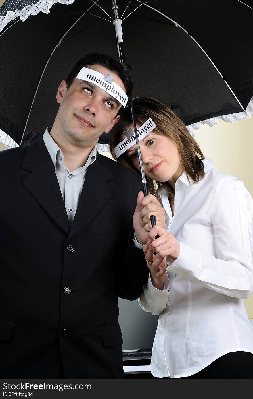 Unemployed man and woman showing identical situation and staying under the same umbrella. Unemployed man and woman showing identical situation and staying under the same umbrella