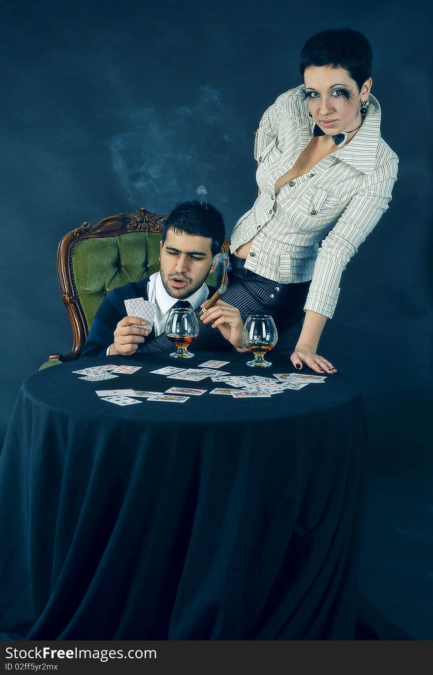 There is cool couple. He smokes cigar and hold glass with cognac. There is cool couple. He smokes cigar and hold glass with cognac.