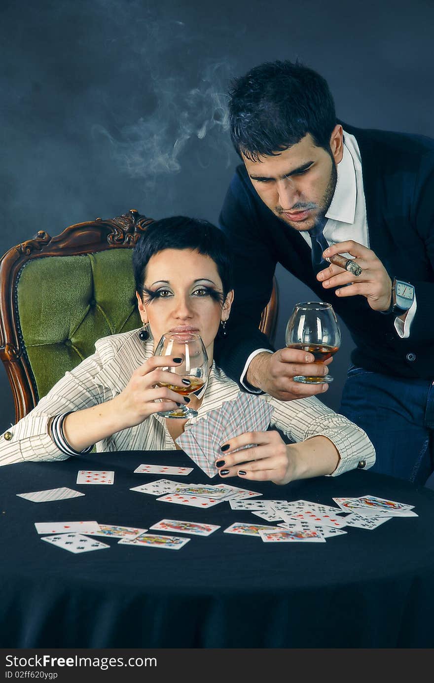 There is cool couple. He smokes cigar and hold glass with cognac. There is cool couple. He smokes cigar and hold glass with cognac.