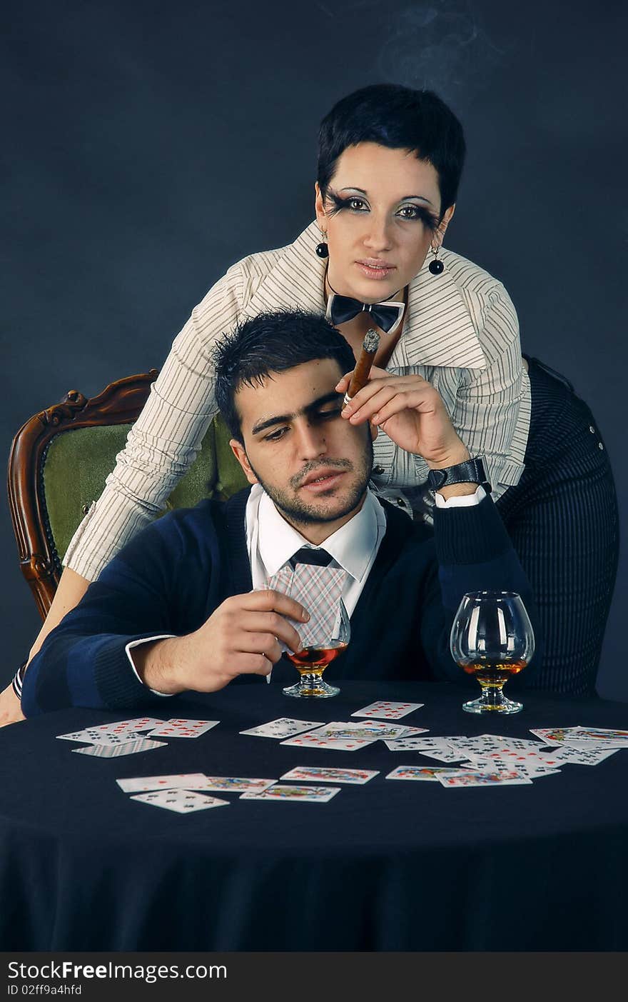 There is cool couple. He smokes cigar and hold glass with cognac. There is cool couple. He smokes cigar and hold glass with cognac.