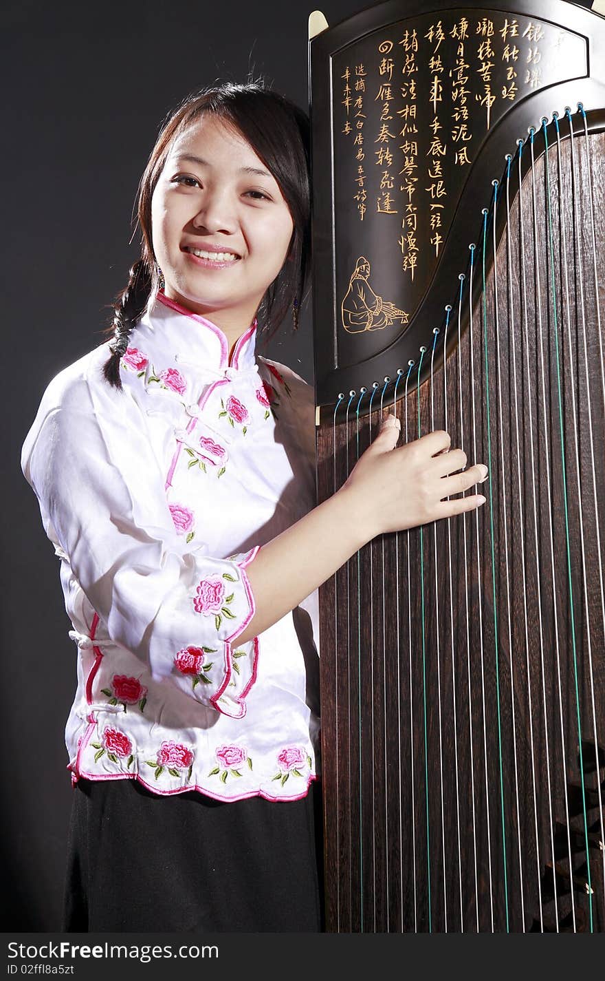 Chinese zither performer in traditional dress with her zither on dark background.
Chinese character on zither is Chinese Tang poetry,also a famous Tang Dynasty poet's calligraphy. It praised the unique charm of the zither. Chinese zither performer in traditional dress with her zither on dark background.
Chinese character on zither is Chinese Tang poetry,also a famous Tang Dynasty poet's calligraphy. It praised the unique charm of the zither