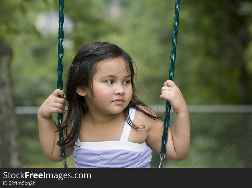 Cute little asian girl with long hair playing on a swing. Cute little asian girl with long hair playing on a swing