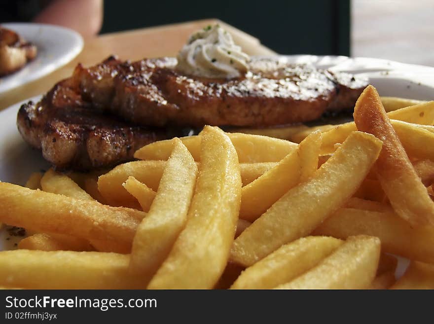 Grilled pork chop with french fries, garnished with garlic butter