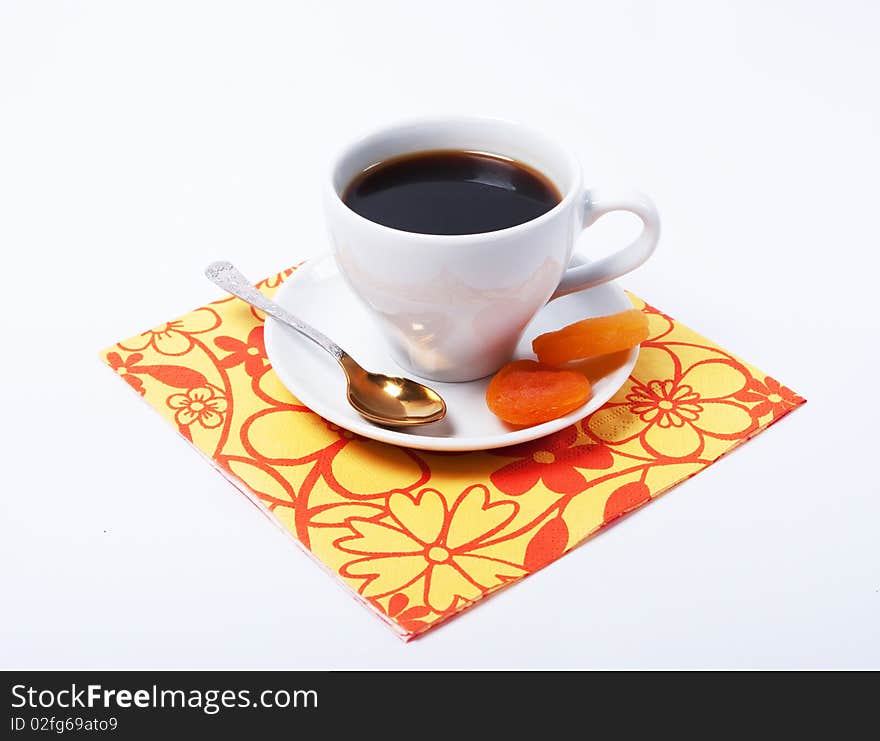 A cup of coffee and two dried apricots served at bright paper tabletop. A cup of coffee and two dried apricots served at bright paper tabletop.