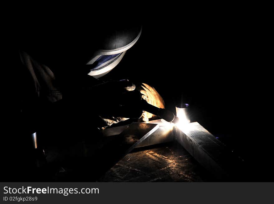 A welder working at shipyard during day. A welder working at shipyard during day