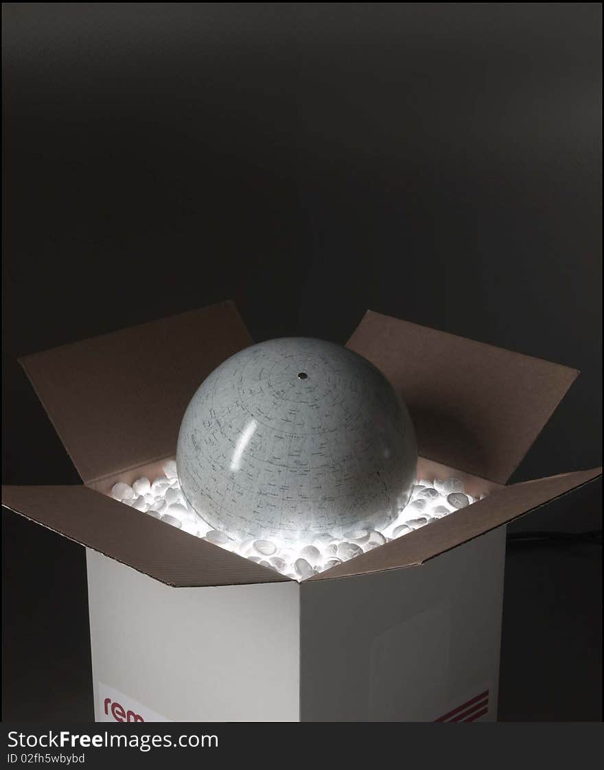 Globe sits inside of an illuminated cardboard box with popcorn for packaging. Globe sits inside of an illuminated cardboard box with popcorn for packaging