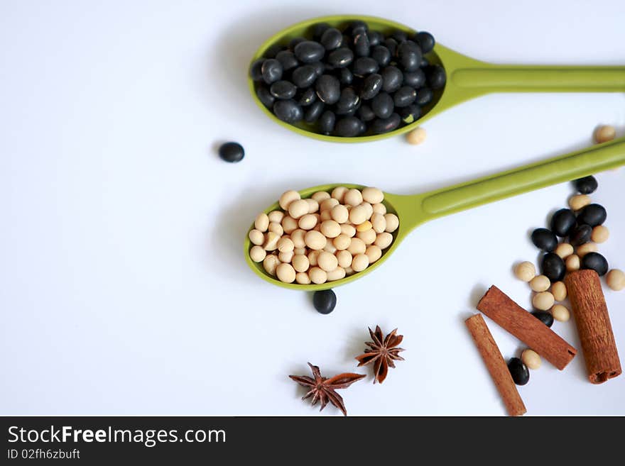 black and yellow beans collect in measuring spoons on white background. black and yellow beans collect in measuring spoons on white background