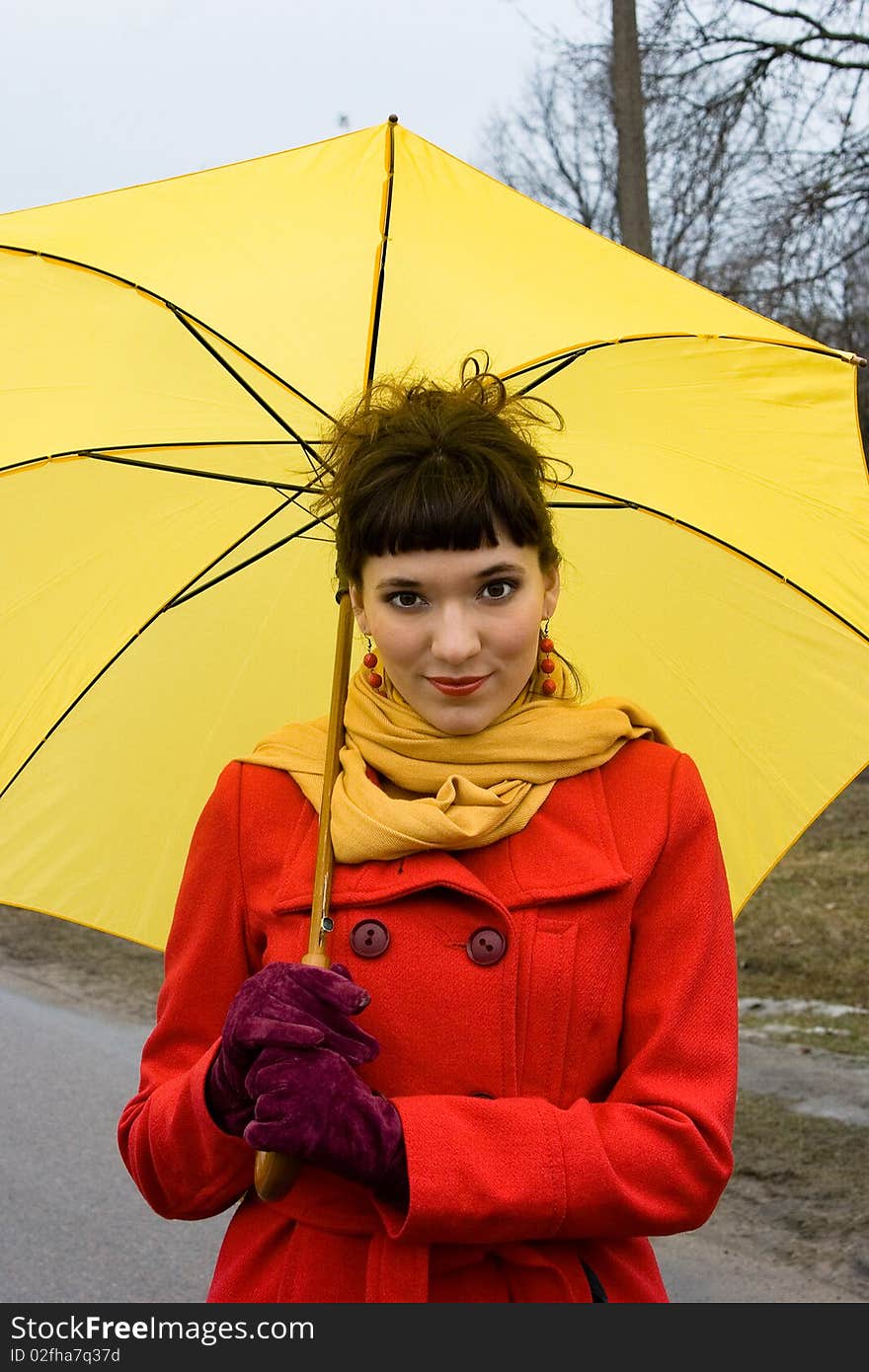 Beautiful girl on red coat with yellow umbrella. Beautiful girl on red coat with yellow umbrella