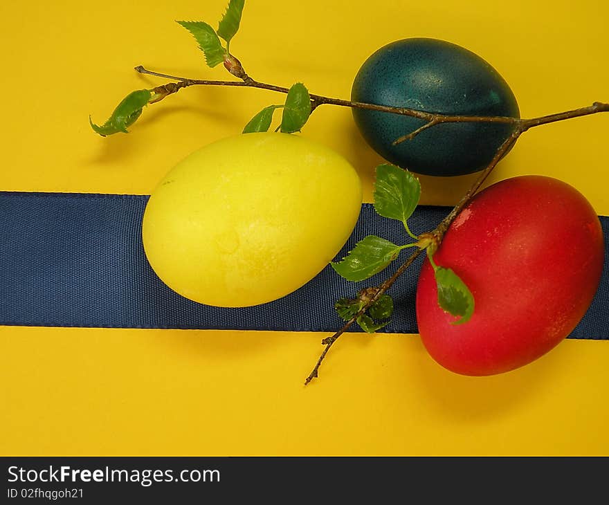 Colored Easter eggs and blue ribbon isolated on yellow