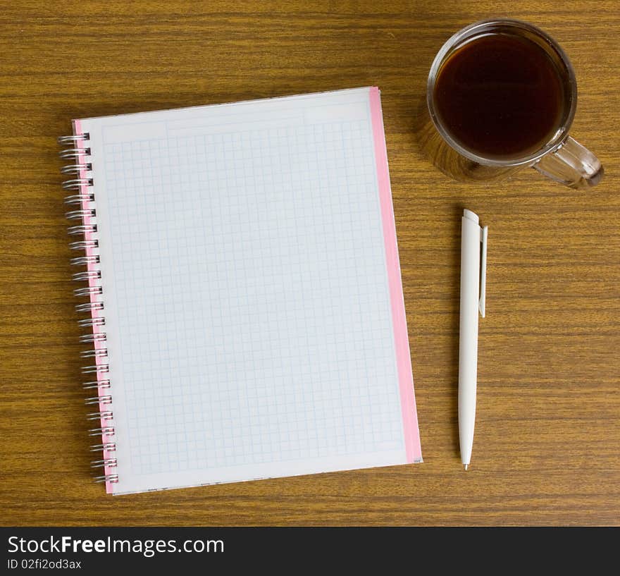 Notebook and a cup coffee on a wooden table